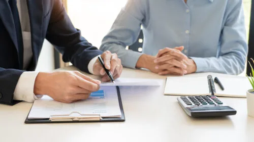 Contratto di avvalimento: l'immagine rappresenta due persone sedute ad una scrivania mentre discutono di un contratto.
